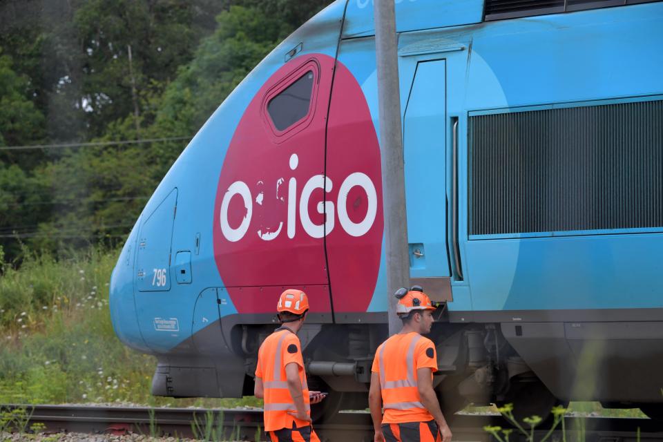 SNCF employees look on as a TGV train moves past them at Vald'yerre on the outskirts of Chartres, northern France, July 26, 2024, after the resumption of high speed train services on the line between Paris and Bordeaux following suspected acts of sabotage. / Credit: JEAN-FRANCOIS MONIER/AFP/Getty