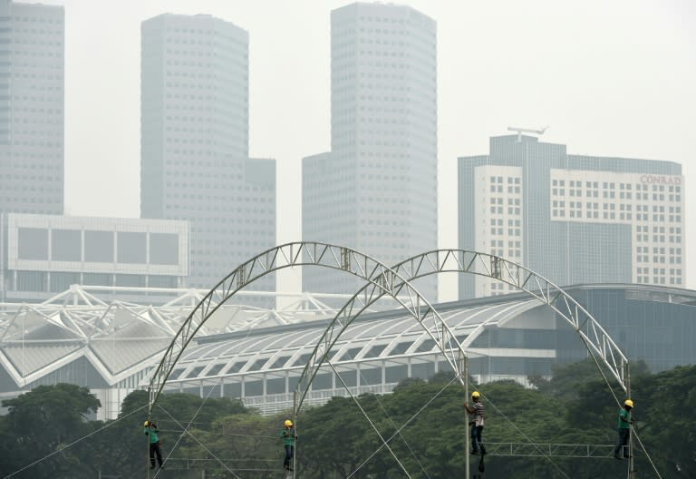 Workers install the frame for a giant tent at "the Padang" as downtown buildings are shrouded in smog in Singapore on October 5, 2015