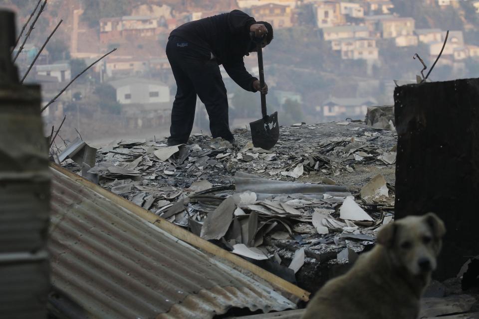 A man clears debris from his destroyed home after a large forest fire reached urban areas in Valparaiso, Chile, Sunday April 13, 2014. Authorities say the fires have destroyed hundreds of homes, forced the evacuation of thousands and claimed the lives of at least seven people. ( AP Photo/ Luis Hidalgo)