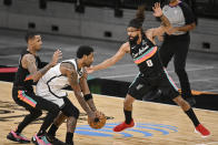 Brooklyn Nets' Kyrie Irving, center, grabs the ball as he is defended by San Antonio Spurs' Patty Mills (8) and Dejounte Murray during the first half of an NBA basketball game, Monday, March 1, 2021, in San Antonio. (AP Photo/Darren Abate)