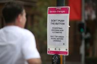 A jogger moves past a sign telling people not to push the crosswalk button in the city centre of Sydney