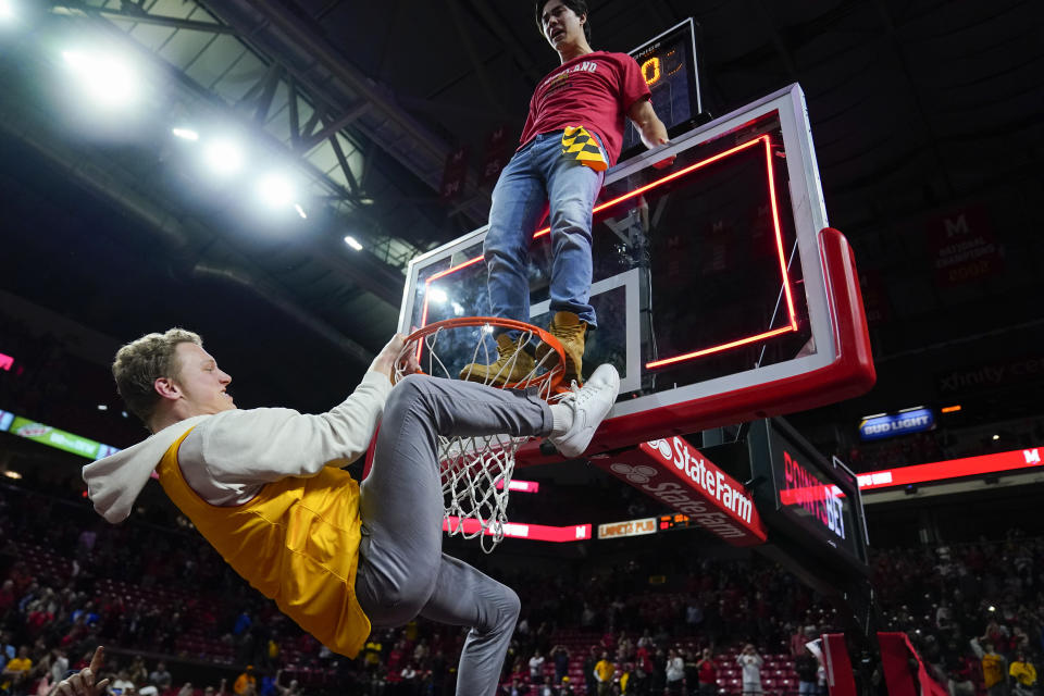 Students climb a rim as a crowd rushes the court after Maryland defeated Purdue 68-54 during an NCAA college basketball game, Thursday, Feb. 16, 2023, in College Park, Md. (AP Photo/Julio Cortez)