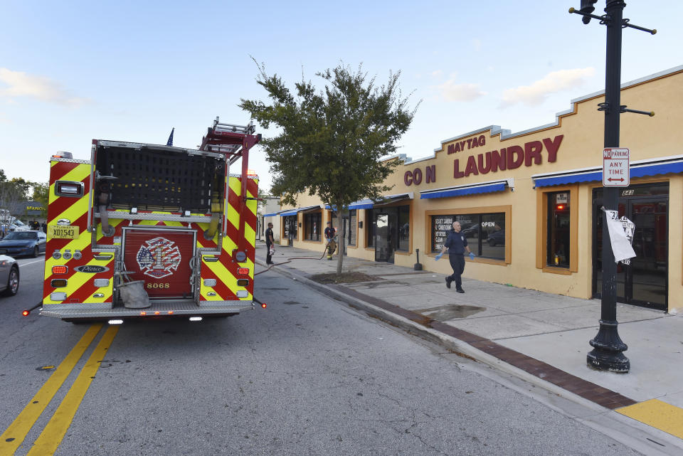 Jacksonville Fire and Rescue personnel use chemicals and hoses to clean the blood outside the Maytag Coin Laundry on A Philip Randolph Boulevard, Sunday, Oct. 21, 2018, in Jacksonville, Fla., after a street shooting earlier in the day, several blocks away from TIAA Bank Field where the Jacksonville Jaguars and Houston Texans played an NFL football game. (Bob Self/The Florida Times-Union via AP)