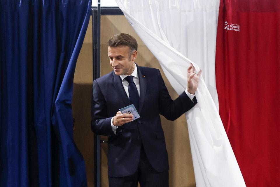 France’s president Emmanuel Macron exits a polling booth, adorned with curtains displaying the colors of the flag of France, to vote in the second round of France’s legislative election at a polling station in Le Touquet, northern France on 7 July 2024 (AFP via Getty)