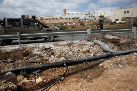 An altered water pipe is seen near a road where a Palestinian boy rides his bicycle near an Israeli Defence Force (IDF) vehicle in the West Bank Jewish settlement of Beit Haggai, near Hebron August 17, 2016. REUTERS/Ronen Zvulun