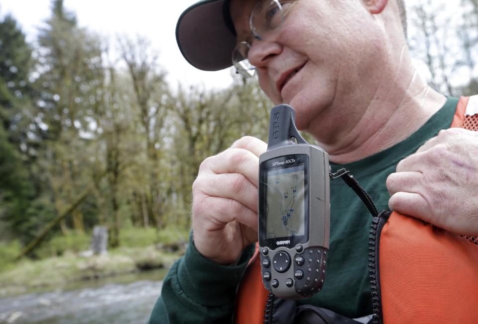 In this photo taken Tuesday, April 15, 2014, fisheries biologist Pete Verhey replaces his GPS unit after marking the location of a salmon spawning nest in Squire Creek, a tributary of the North Fork of the Stillaguamish River, near Darrington, Wash. Finding the nest, called a redd, is an encouraging sign that steelhead trout may be making their way upstream from Oso., Wash., above where a massive landslide decimated a riverside neighborhood a month ago and pushed several football fields worth of sediment down the hillside and across the river. As search crews continue to look for people missing in the slide, scientists also are closely monitoring how the slide is affecting federally endangered fish runs, including Chinook salmon and steelhead. (AP Photo/Elaine Thompson)