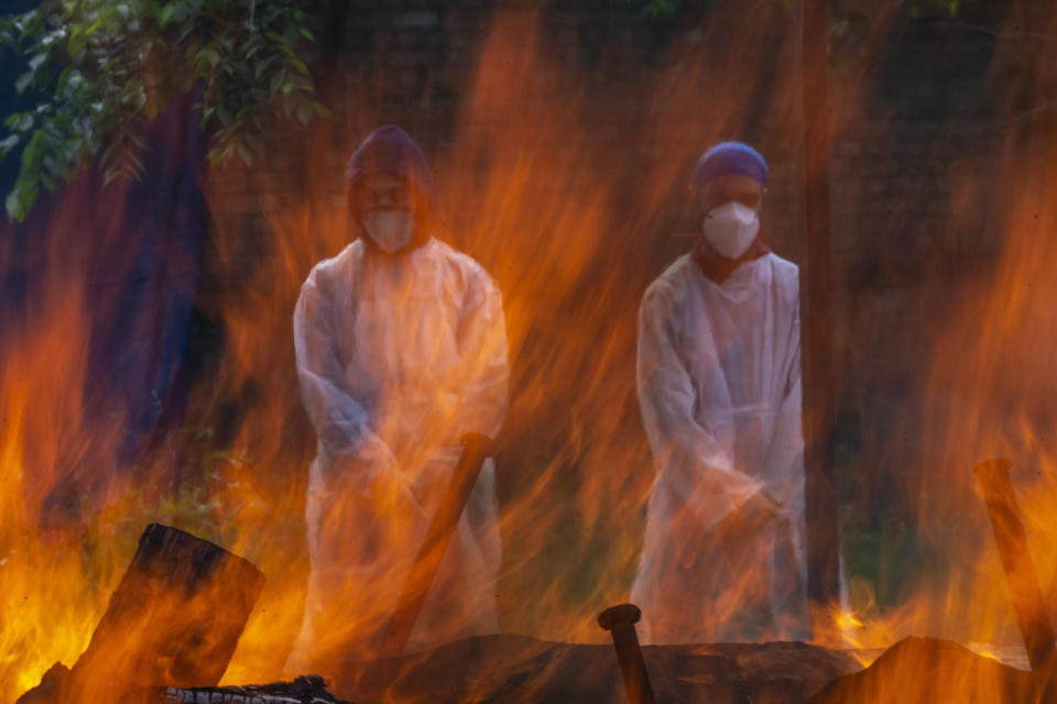 Relatives in protective suits stand next to the burning pyre of a person who died of COVID-19, at a crematorium in Srinagar, Indian controlled Kashmir, Tuesday, May 25, 2021. (AP Photo/Dar Yasin)