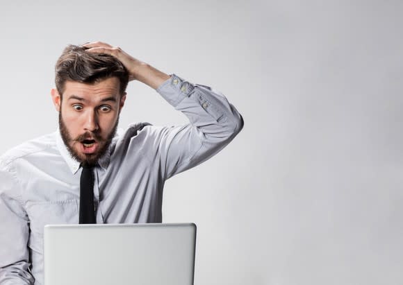 Professional man looking at laptop with shocked expression