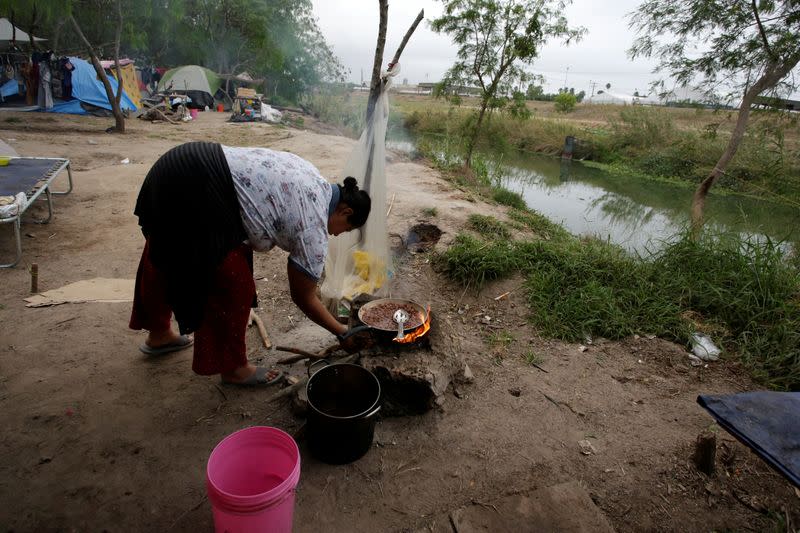 A Central American migrant cooks beans at an encampment of more than 2,000 migrants, as local authorities prepare to respond to the coronavirus disease (COVID-19) outbreak, in Matamoros