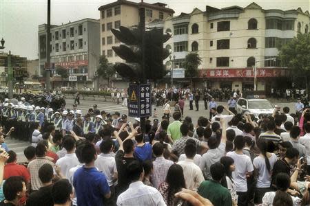 Workers protest during a strike as police stand guard at a crossroads near the factory area of Yue Yuen Industrial, in Dongguan, Guangdong province in this April 18, 2014 file photo. REUTERS/Stringer/Files