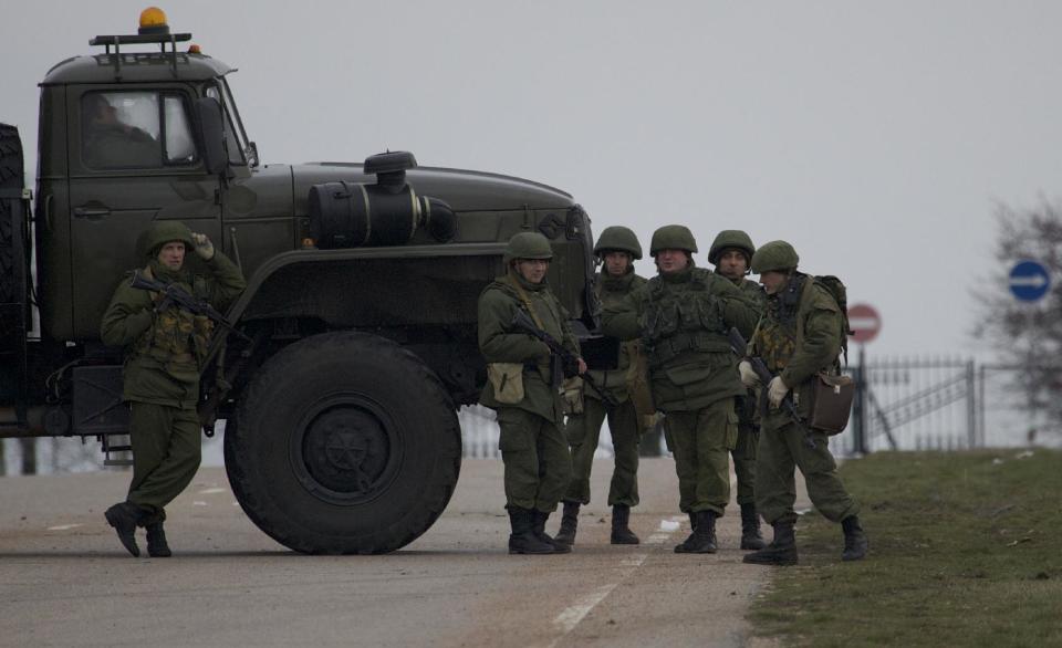 Unidentified gunmen wearing camouflage uniforms block the road toward the military airport at the Black Sea port of Sevastopol in Crimea, Ukraine, Friday, Feb. 28, 2014. Heightened security is evident with Russian military around Sevastopol, the location for Russia military bases, military airport and Naval Base, while unidentified armed men wearing uniforms without insignia were patrolling another airport serving the regional capital, Ukraine's new Interior Minister Arsen Avakov said on Friday. (AP Photo/Ivan Sekretarev)