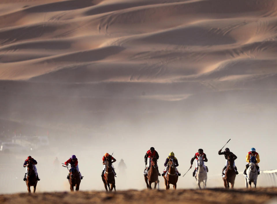 <p>Jockeys compete in a race for purebred Arab horses during the Moreeb Dune Festival on Jan. 1 in the Liwa desert, some 250 kilometers west of Abu Dhabi. (Photo: Karim Sahib/AFP/Getty Images) </p>