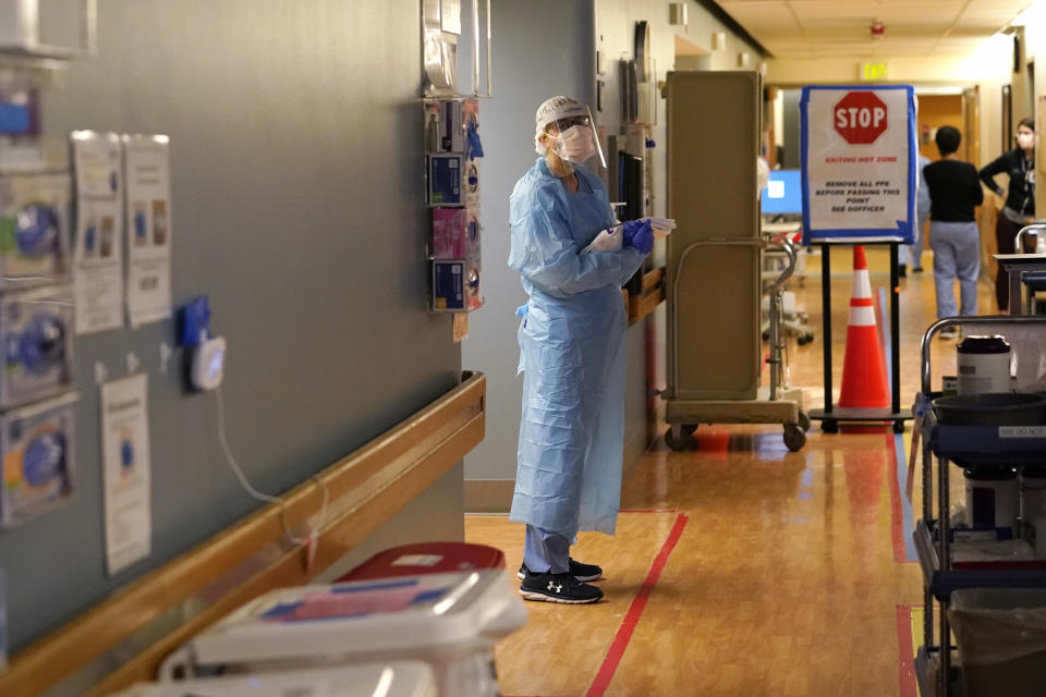 FILE - In this Jan. 26, 2021, file photo, registered nurse Diane Miller stands in the "hot zone," defined by red tape on the floor, as she waits to exchange equipment with a colleague who will remain on the other side of the tape in the COVID acute care unit at UW Medical Center-Montlake in Seattle. Coronavirus hospitalizations are falling across the United States, but deaths have remained stubbornly high. (AP Photo/Elaine Thompson, File)