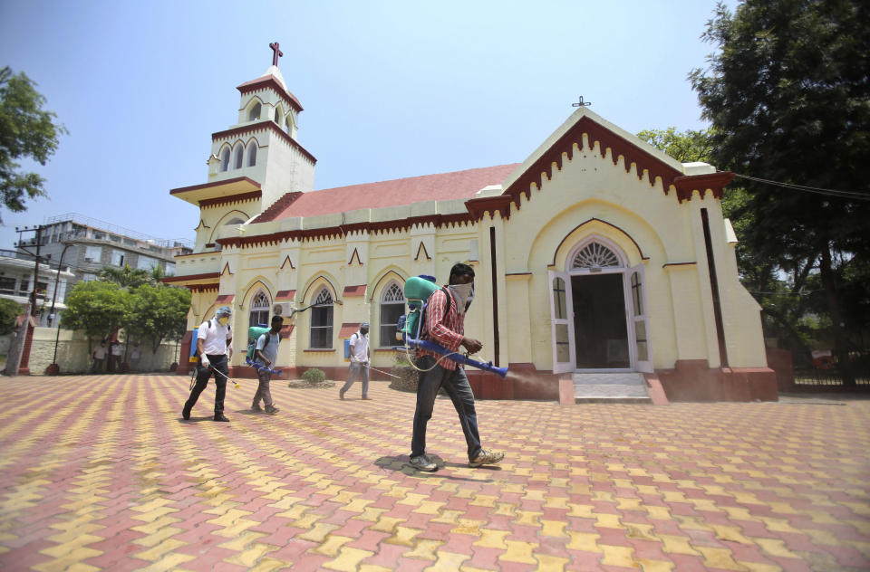 Indian volunteers spray disinfectants at a church in Jammu, India, Sunday, June 7, 2020. India whose coronavirus caseload is fifth highest in the world is Monday reopening places of worship after a period of more than two months lockdown. (AP Photo/Channi Anand)