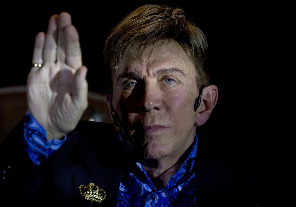 Osmel Sousa uses his hand to block a spotlight as he listens to a question during his news conference in Caracas, Venezuela, Monday, June 25, 2018. Venezuela’s beauty czar announced on Monday his return to beauty contests with a new competition that will include a reality show and will be titled “El concurso,” or The Contest, and will begin recording in August. Sousa, 71, left the Miss Venezuela organization this year after directing the beauty contest for almost four decades. (AP Photo/Fernando Llano)