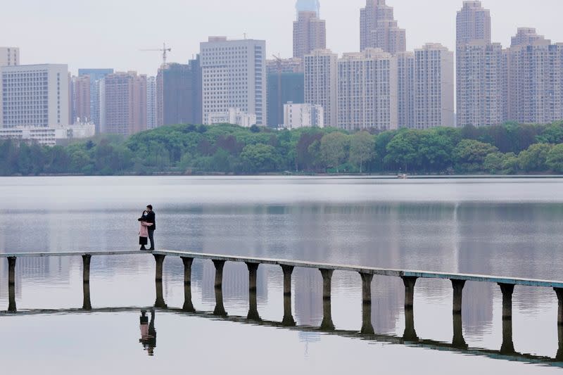 People wearing face masks hug on the East Lake in Wuhan