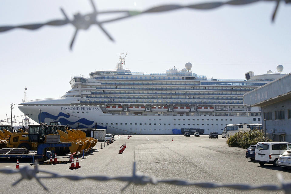 The quarantined ship Diamond Princess is pictured through barbed wire at Yokohama port in Yokohama, near Tokyo Monday, Feb. 17, 2020. Japanese officials have confirmed 99 more people infected by the new virus aboard the ship, the Health Ministry said Monday. (Mayuko Isobe/Kyodo News via AP)