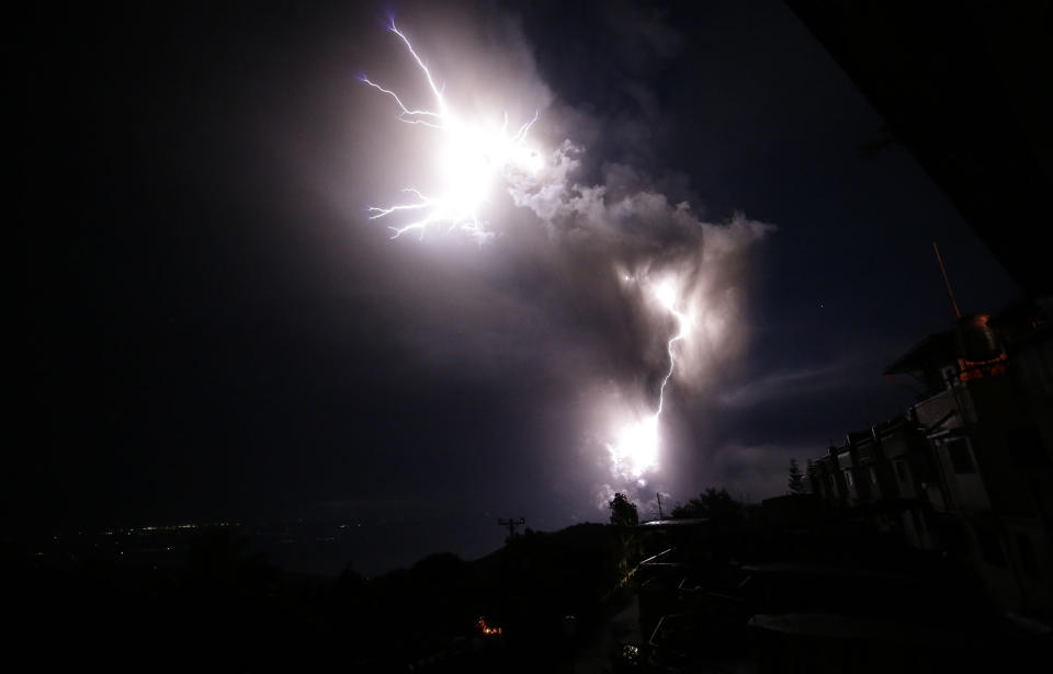 Lightning strikes beside the ash cloud as Taal Volcano erupts Sunday Jan. 12, 2020, in Tagaytay, Cavite province, outside Manila, Philippines. A tiny volcano near the Philippine capital that draws many tourists for its picturesque setting in a lake belched steam, ash and rocks in a huge plume Sunday, prompting thousands of residents to flee and officials to temporarily suspend flights. (AP Photo/Aaron Favila)