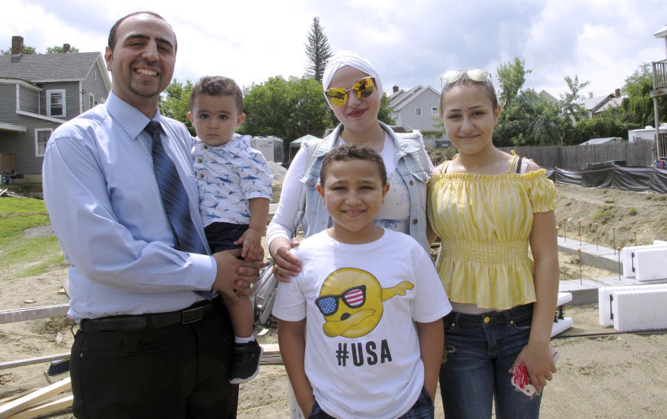 In this July 31, 2019 photo, Hussam Alhallak, left, sons Danyal, held by his father, and Muhammad, wife Hazar Mansour and daughter Layan, right, stand at the site of their new home being built by Habitat for Humanity of Rutland County in Rutland, Vt. The family fled the war in Syria and are making a life for themselves in Vermont. (AP Photo/Lisa Rathke)