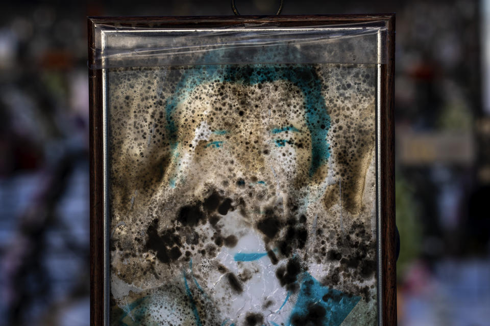 A worn-out portrait of Volodymyr Mandrik, 83, sits on his grave at a cemetery in Irpin, Ukraine, on the outskirts of Kyiv, on Thursday, Feb. 9, 2023. His wife, Halyna, had photos of her husband and herself printed and framed long before the war. She wanted to make things easy for their children in the event of their deaths. The photos would be there, in plastic bags ready to be nailed to the cross when their time came. He was buried on March 22, 2022. (AP Photo/Emilio Morenatti)