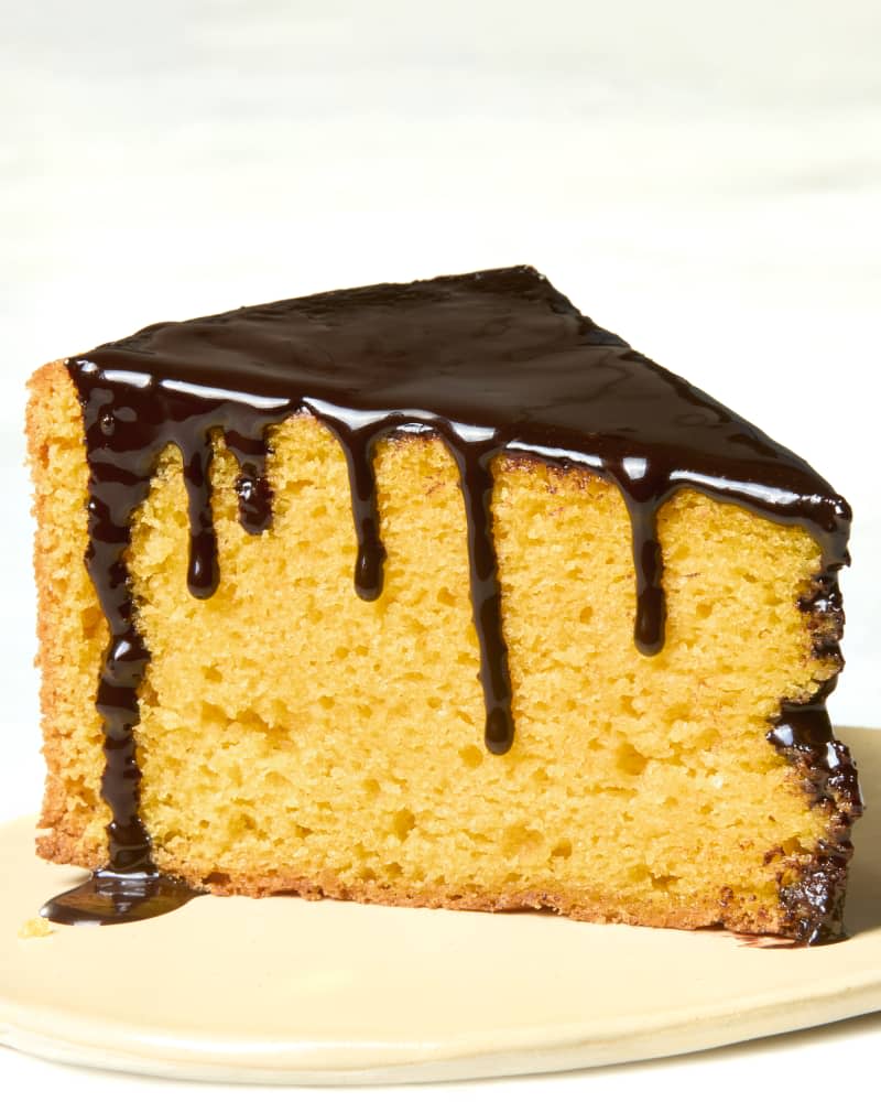 head on shot of a slice of bolo de cenoura on a flat beige plate, with the chocolate glaze dripping.