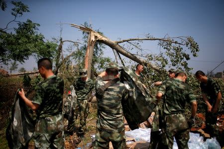 Paramilitary policemen stand next to damaged trees after a tornado hit Funing on Thursday, in Yancheng, Jiangsu province, June 25, 2016. REUTERS/Aly Song