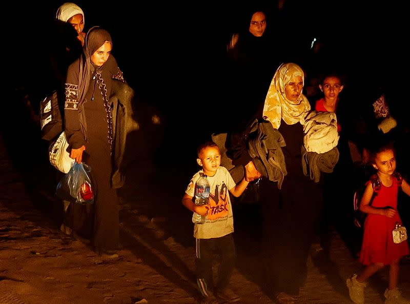 Palestinians, who fled the eastern part of Khan Younis, walk, after they were ordered by Israeli army to evacuate their neighbourhoods, amid Israel-Hamas conflict, in Khan Younis