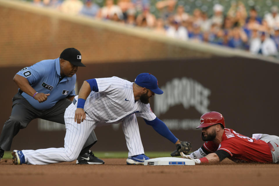 Chicago Cubs second baseman David Bote, center, tags out Cincinnati Reds' Jesse Winker, right, at second base during the first inning of a baseball game, Monday, July 26, 2021, in Chicago. (AP Photo/Paul Beaty)