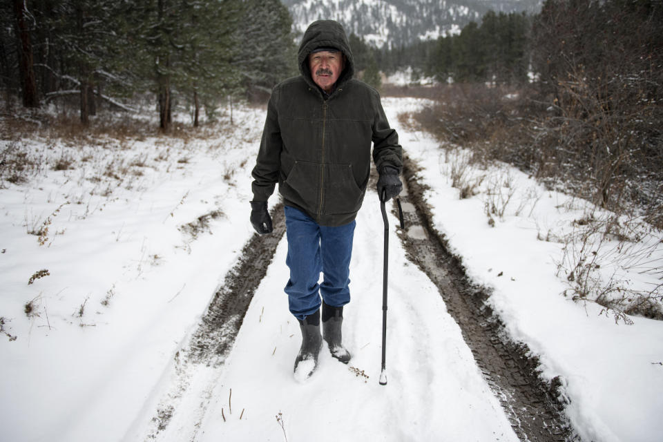 Richard King, 70, walks down a muddy road on the family ranch near Zortman, Mont., on Sunday, Dec. 8, 2019. "It's called complete serenity." King said of living on the ranch. "Its close as you can get to God living here." (AP Photo/Tommy Martino)