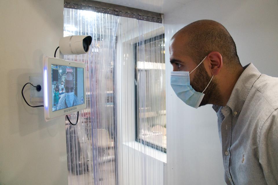 In this Monday, April 27, 2020 photo, a worker examines a gate system made by Guard ME that conducts temperature checks and fogs disinfectants on users, in Dubai, United Arab Emirates. As confirmed coronavirus cases spike, the United Arab Emirates is opening up its cavernous malls and restaurants in a gamble to stimulate its economy while still trying to fight off the pandemic. That's led to a new normal here of temperature checks, social distancing monitors at supermarkets and marked-off empty seats on the city's driverless Metro. (AP Photo/Jon Gambrell)