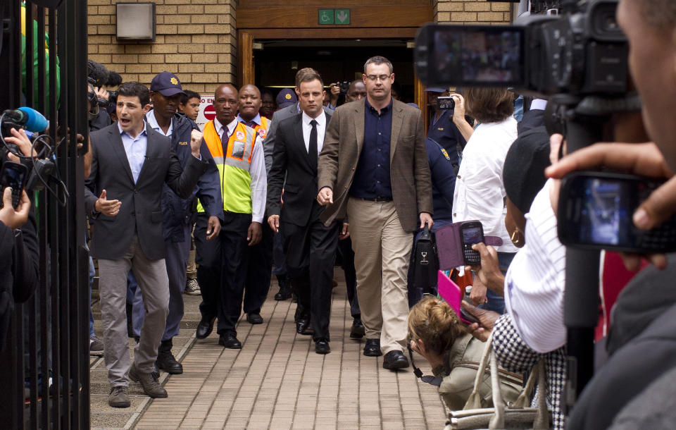 Oscar Pistorius, center, walks out of the high court in Pretoria, South Africa, Friday, March 14, 2014. Pistorius is charged with murder for the shooting death of his girlfriend, Reeva Steenkamp, on Valentines Day in 2013. (AP Photo/Themba Hadebe)