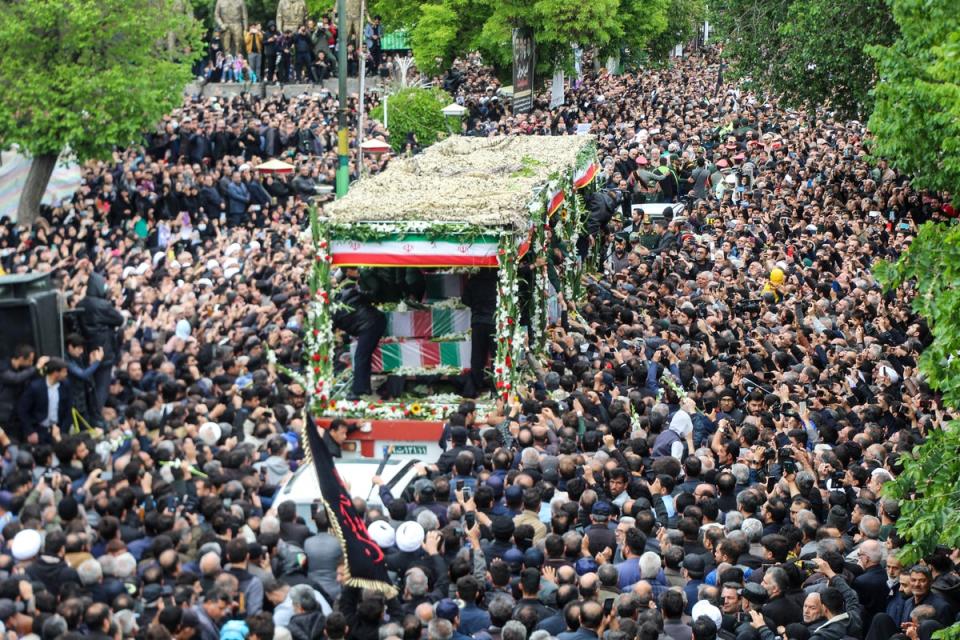 People walk alongside a lorry carrying President Ebrahim Raisi’s coffin (FARS NEWS AGENCY/AFP via Getty I)