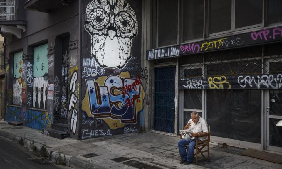 Man smoking outside boarded-up shop Atens