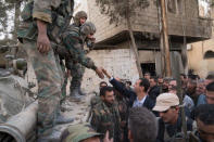 Syrian President Bashar al-Assad reaches out to shake the hand of a Syrian army soldier in eastern Ghouta, Syria, March 18, 2018. SANA/Handout via REUTERS