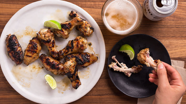 Hand eating grilled chicken wings