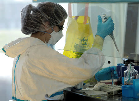 FILE PHOTO: A lab assistant performs an experiment during an inauguration visit of a new P3 level research laboratory against tuberculosis at the School of Life Sciences of the Swiss Federal Institute of Technology (EPFL) near Lausanne, Switzerland, March 17, 2010. REUTERS/Denis Balibouse /File Photo