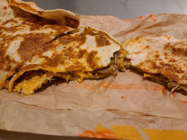 quarters of a steak quesadilla resting on a wrapper from taco bell