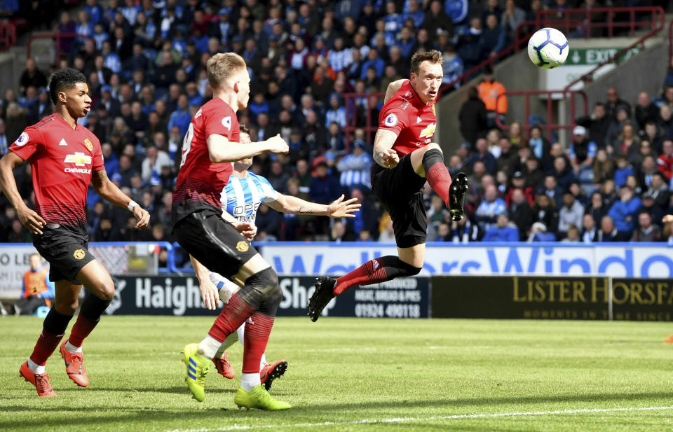 Manchester United's Phil Jones, right, goes for the ball during the English Premier League soccer match against Huddersfield Town at the John Smith's Stadium, Huddersfield, England, Sunday May 5, 2019. (Anthony Devlin/PA via AP)