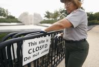 A National Park worker removes a closed sign at the Martin Luther King Jr. Memorial after it was re-opened to the public in Washington October 17, 2013. The White House moved quickly early on Thursday to get the U.S. government back up and running after a 16-day shutdown, directing hundreds of thousands of workers to return to work. REUTERS/Kevin Lamarque