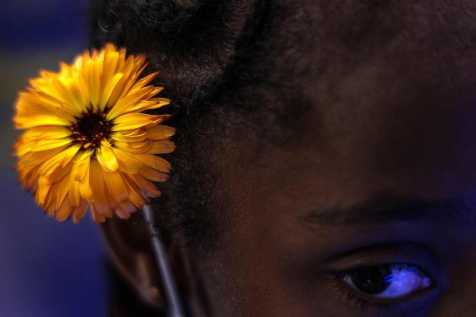 Una niña se coloca una flor comestible en el pelo durante una visita a la granja hidropónica de Lotus Village, en el vecindario de Overtown, Miami.