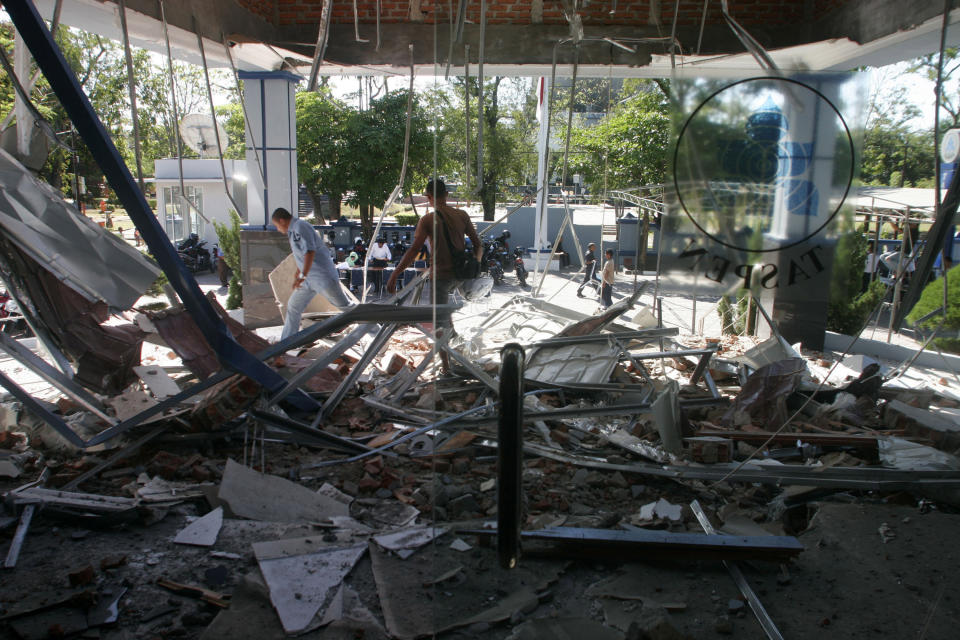 People walk through debris from Wednesday's strong earthquake at an office building in Banda Aceh, Aceh province, Sumatra island, Indonesia, Thursday, April 12, 2012. Cries of panic and fervent prayers rang out Wednesday as Indonesians rushed toward high ground after two strong earthquakes raised fears of a killer tsunami. (AP Photo/Heri Juanda)