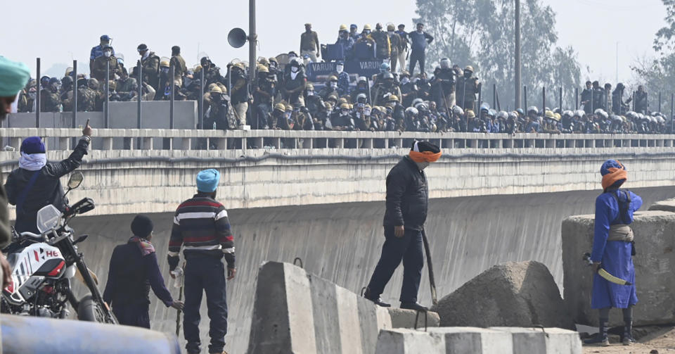 Farmers confront police force as they are stooped during their march to New Delhi near the Punjab-Haryana border at Shambhu, India, Tuesday, Feb.13, 2024. Farmers are marching to the Indian capital asking for a guaranteed minimum support price for all farm produce. (AP Photo/Rajesh Sachar)