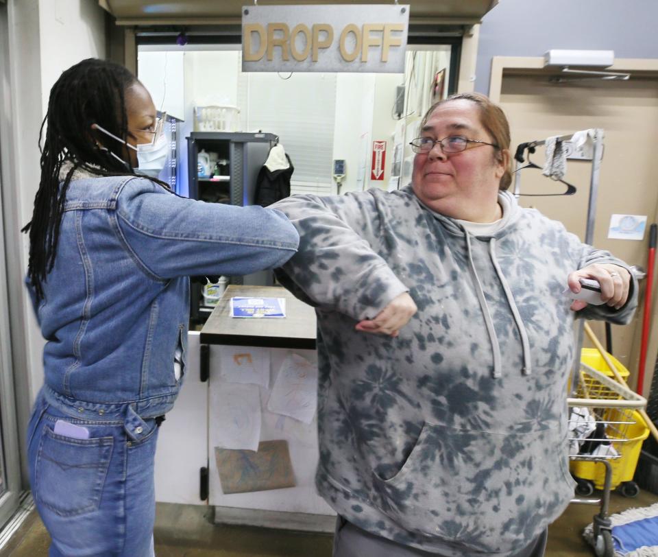 Josy Jones of the West Hill Neighborhood Organization elbow bumps Becky Bydo, manager at Balch St. Laundromat, after leaving a survey flyer and bus passes for Bydo to give to customers.