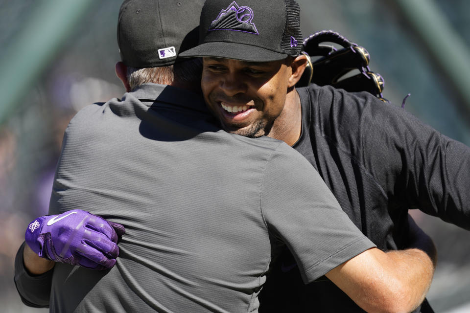 Colorado Rockies head trainer Keith Dugger, left, hugs outfielder Wynton Bernard who warms up before a baseball game against the Arizona Diamondbacks, Friday, Aug. 12, 2022, in Denver. (AP Photo/David Zalubowski)