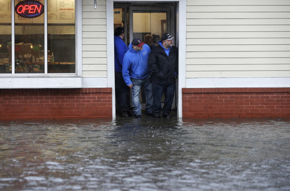 <p>People stand at the entrance to a pizza shop as water floods a street, in Scituate, Mass., Friday, March 2, 2018. (Photo: Steven Senne/AP) </p>