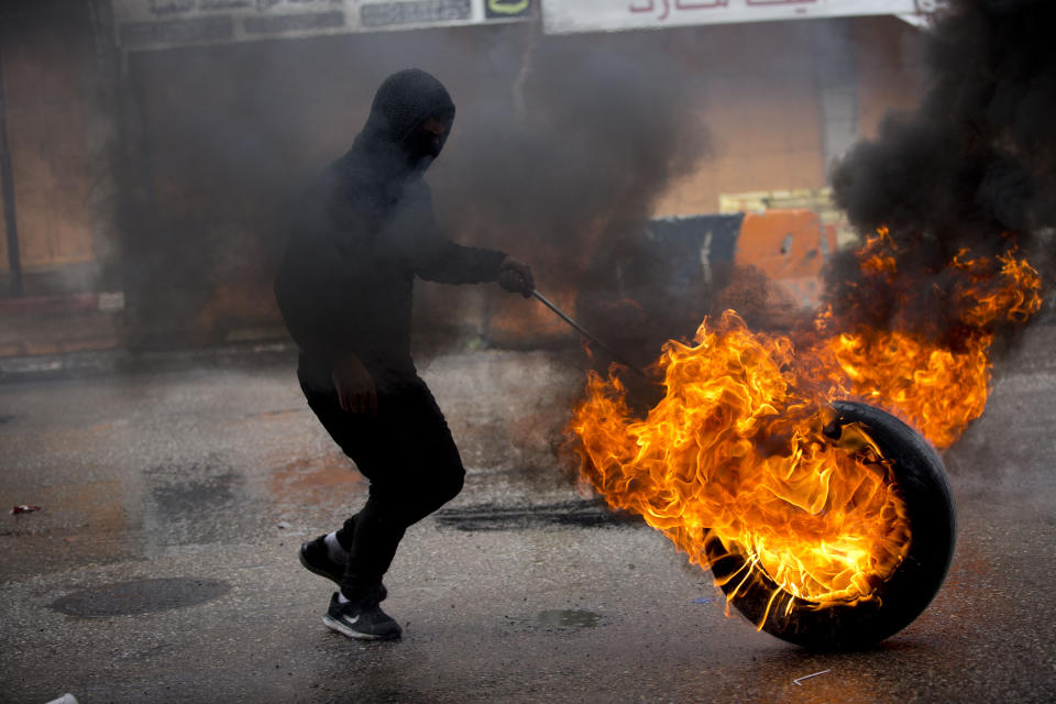 A Palestinian takes cover during clashes with Israeli troops during a protest over Israeli settlement activity Monday, Dec. 9, 2019, in the West Bank city of Hebron. (AP Photo/Majdi Mohammed)