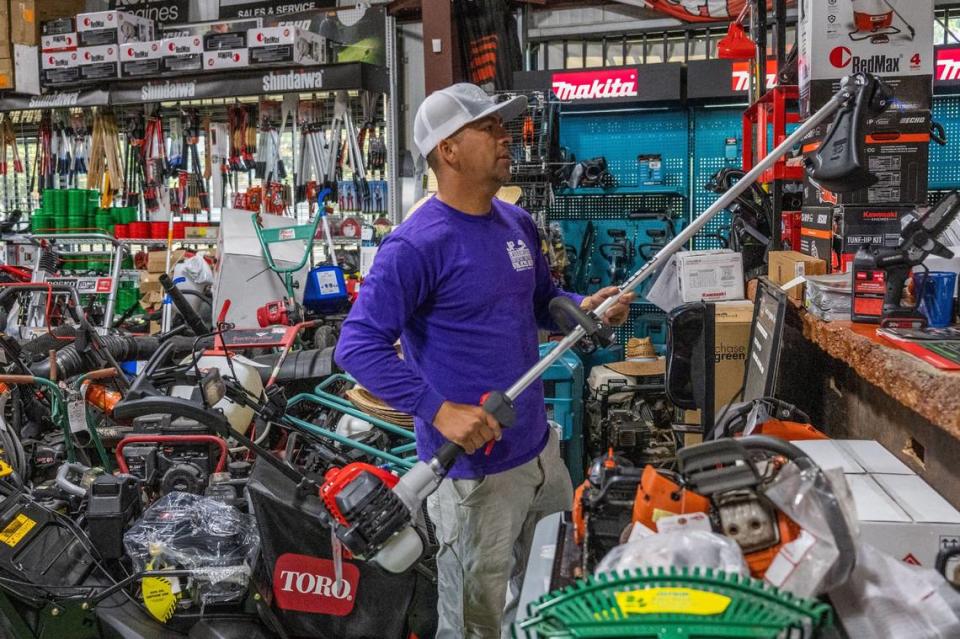 Audel Palomares of Sacramento selects a gas-powered trimmer to purchase at Del Sol Landscape Power Tools in Sacramento in August. A ban on sales of new gas-powered landscaping equipment starts in 2024.