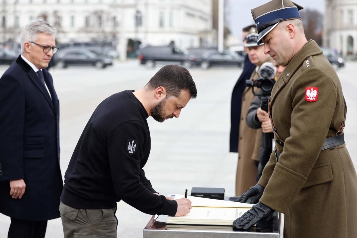 Ukrainian President Volodymyr Zelensky signs a commemorative book after a wreath-laying ceremony at The Tomb of the Unknown Soldier in Warsaw (AFP via Getty Images)