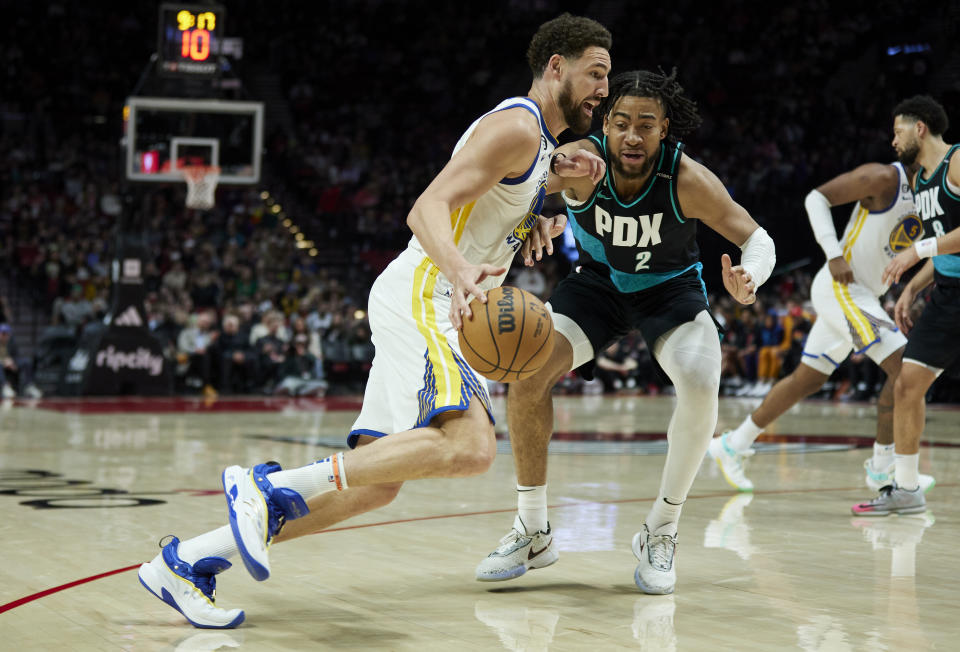 Golden State Warriors guard Klay Thompson, left, dribbles past Portland Trail Blazers forward Trendon Watford during the second half of an NBA basketball game in Portland, Ore., Sunday, April 9, 2023. (AP Photo/Craig Mitchelldyer)