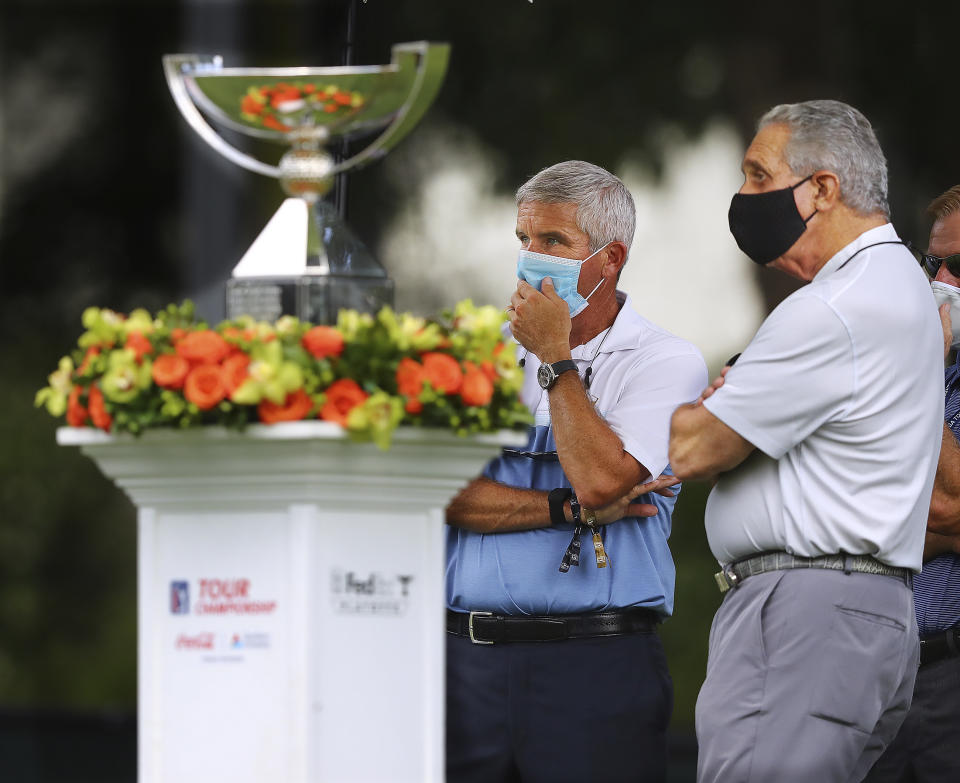 PGA Tour commissioner Jay Monahan, left, and Atlanta Falcons team owner Arthur Blank, right, are on the first tee next to the FedEx Cup trophy to welcome golfers during the first round of the Tour Championship golf tournament at East Lake Golf Club on Friday, Sept. 4, 2020, in Atlanta. (Curtis Compton/Atlanta Journal-Constitution via AP)